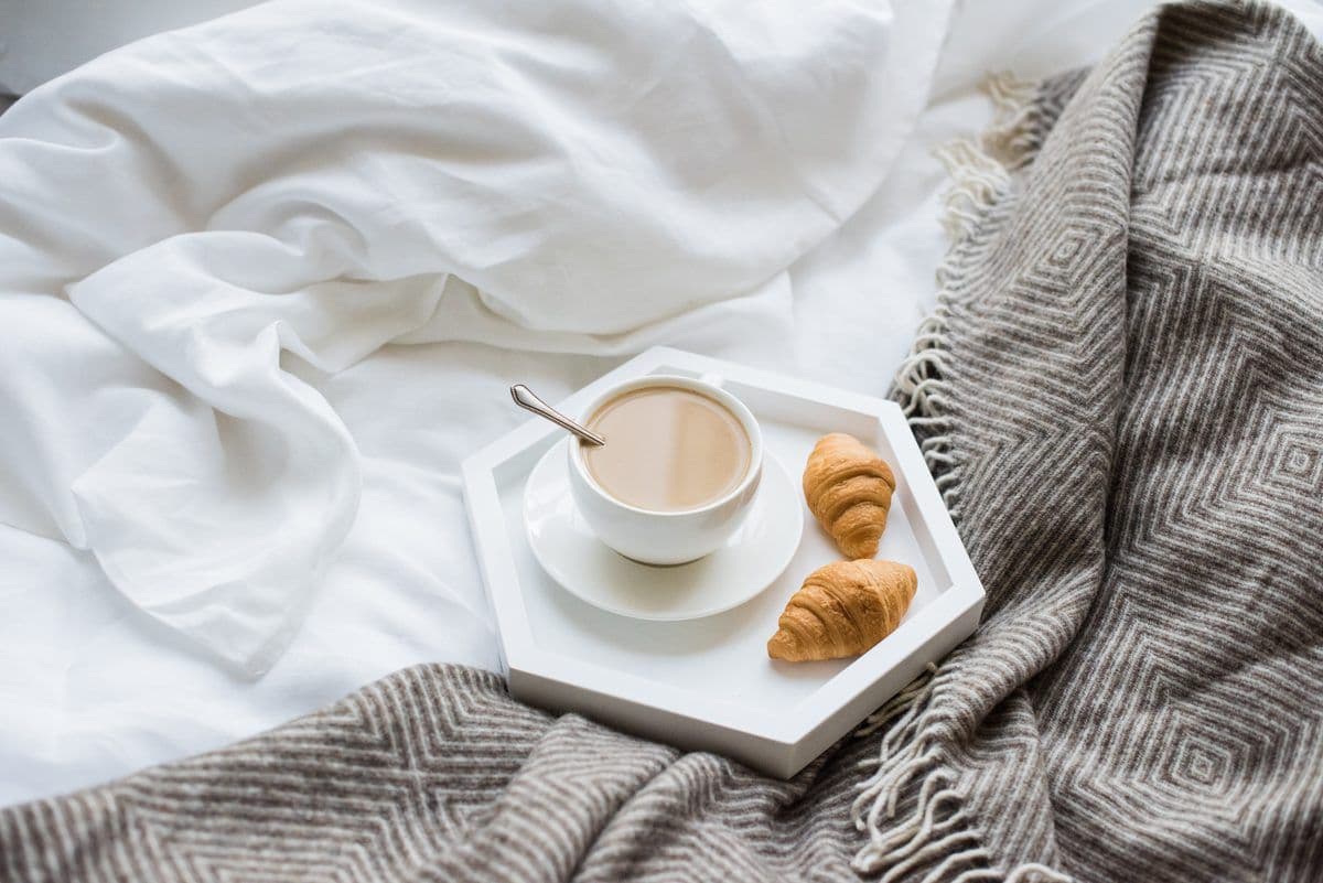 Bett mit weißer Bettwäsche und Frühstückstablett